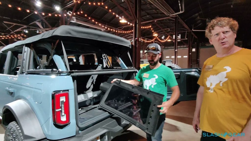 Man inspecting removable door of blue SUV.