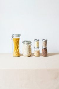 Jars of dry pasta and grains on table