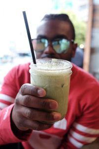 Person holding a green smoothie in a jar.