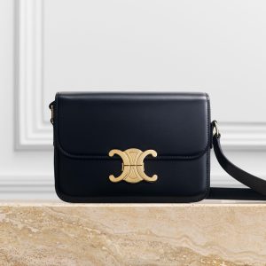 Elegant black handbag with gold clasp on table.