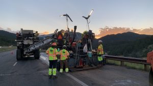 Workers repairing road at sunset in mountains.