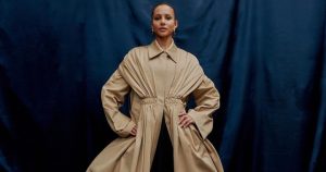 Person in elegant beige dress against blue background.