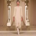 Model in elegant cream dress on ornate runway