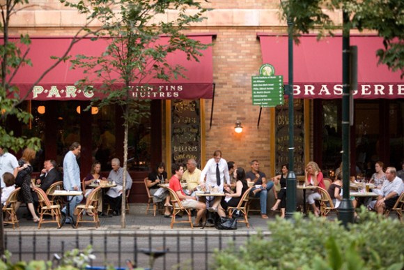 People dining outside a bustling city restaurant.